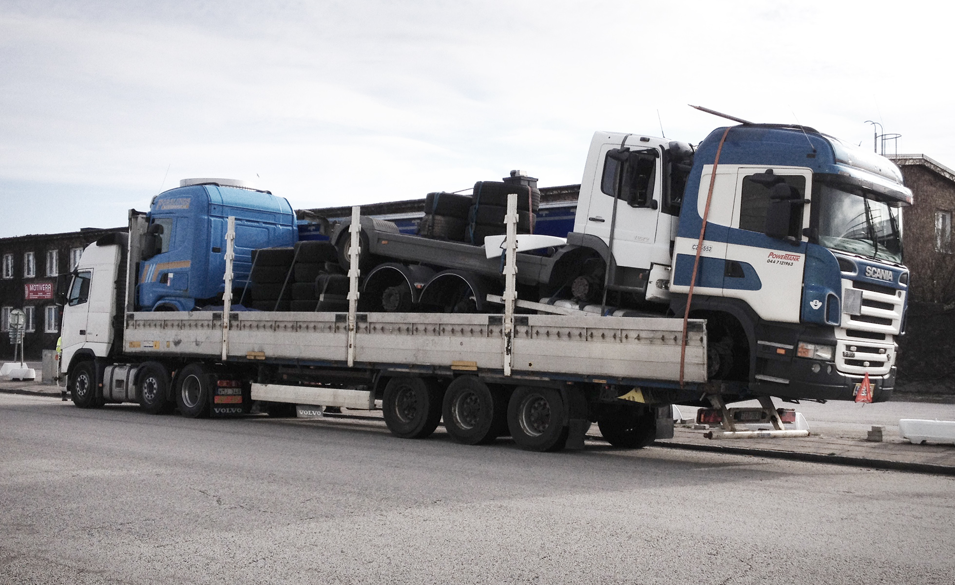 Tre lastbilar med körförbud som är lastade på en lastbil, fästa med enbart spännband. Även lastbilen som de andra fordonen står på har körförbud. Sannolikt ska de transporteras otillåtet utomlands. Foto: Miljöförvaltningen Malmö